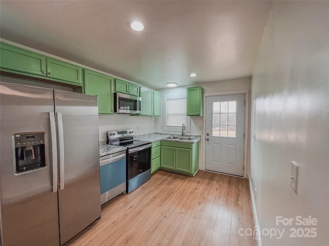 kitchen with light wood-type flooring, a sink, recessed lighting, stainless steel appliances, and green cabinetry