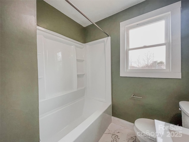 bathroom featuring marble finish floor, toilet, baseboards, and washtub / shower combination