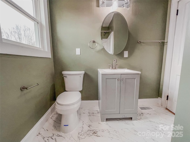 bathroom with vanity, toilet, baseboards, and marble finish floor