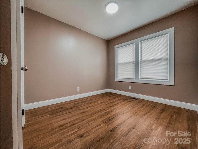 unfurnished room featuring visible vents, baseboards, and wood finished floors