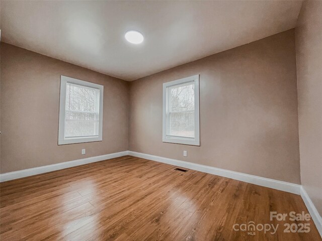 unfurnished room with visible vents, baseboards, and wood finished floors