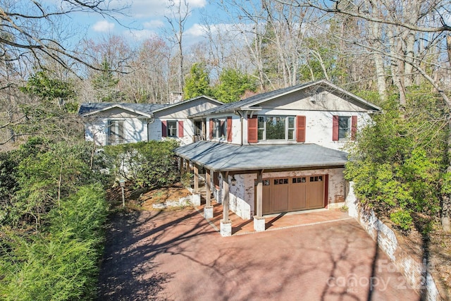 view of front of property with driveway, a chimney, and a garage