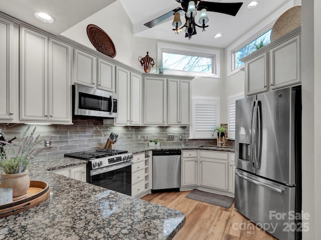 kitchen with a sink, dark stone countertops, tasteful backsplash, and stainless steel appliances