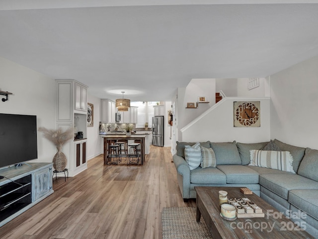 living room featuring visible vents, light wood-style floors, and stairs