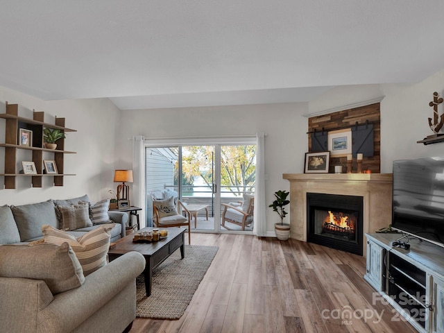 living room with a lit fireplace and wood finished floors