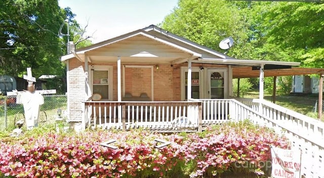 bungalow-style home featuring a carport, fence, and covered porch