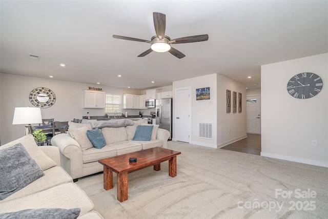 living area with ceiling fan, recessed lighting, visible vents, and light carpet