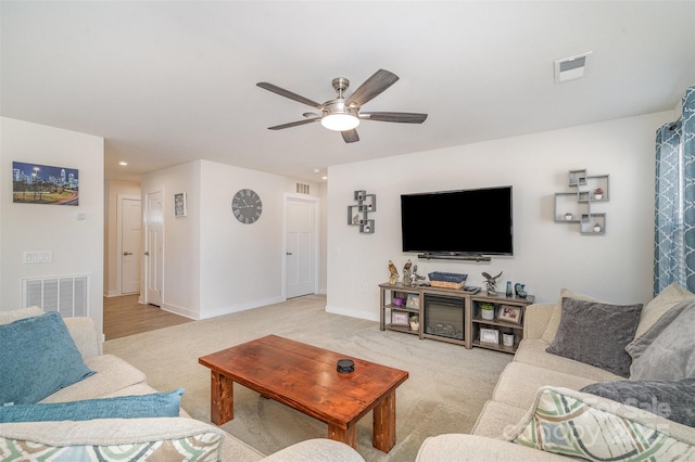 living room featuring light colored carpet, a ceiling fan, and visible vents