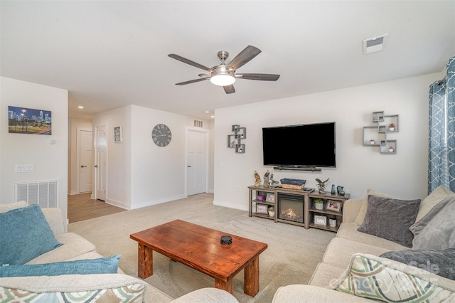 living room featuring visible vents, light carpet, and a ceiling fan