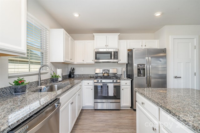 kitchen with light wood-type flooring, a sink, white cabinetry, recessed lighting, and appliances with stainless steel finishes