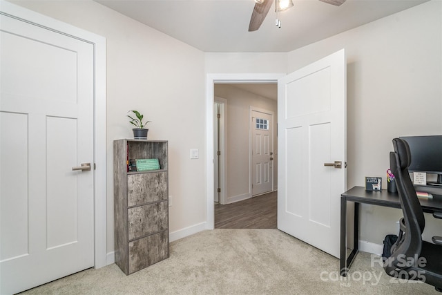 carpeted office space featuring a ceiling fan and baseboards