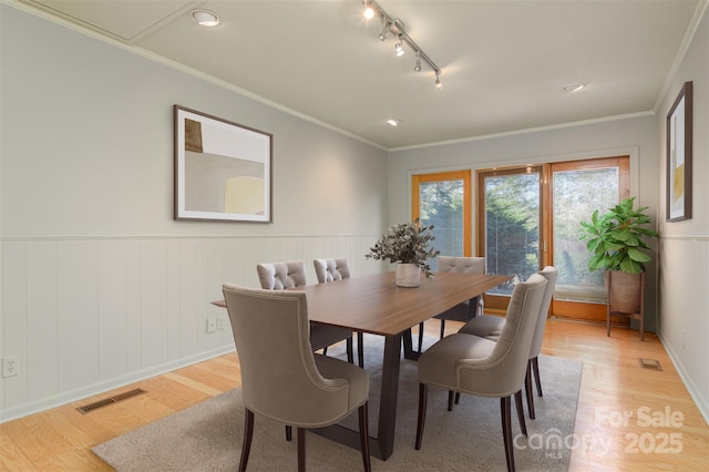 dining area featuring visible vents, crown molding, and light wood-type flooring