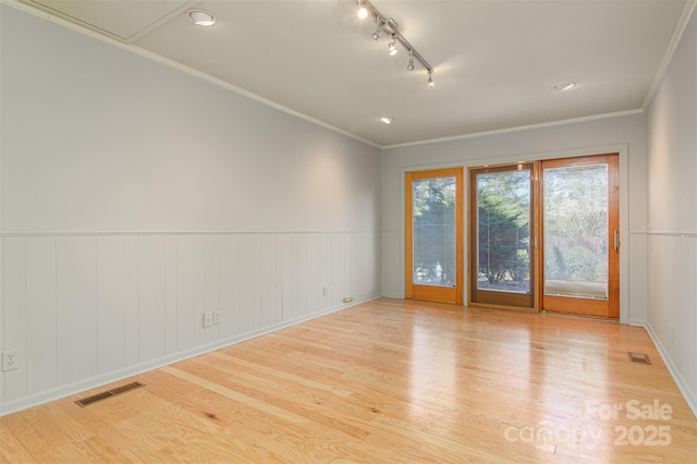 spare room featuring crown molding, light wood-style flooring, and visible vents