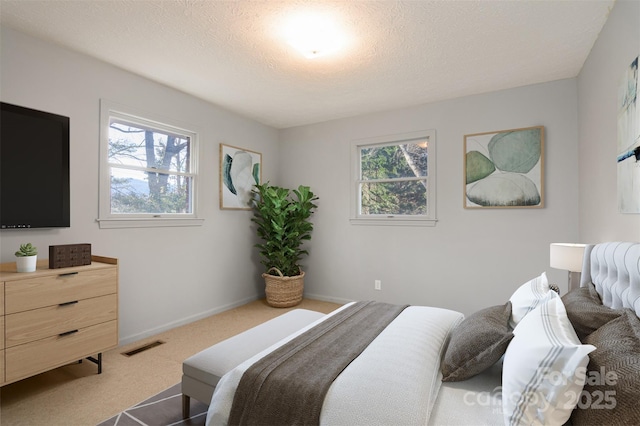 bedroom with visible vents, multiple windows, a textured ceiling, and carpet flooring