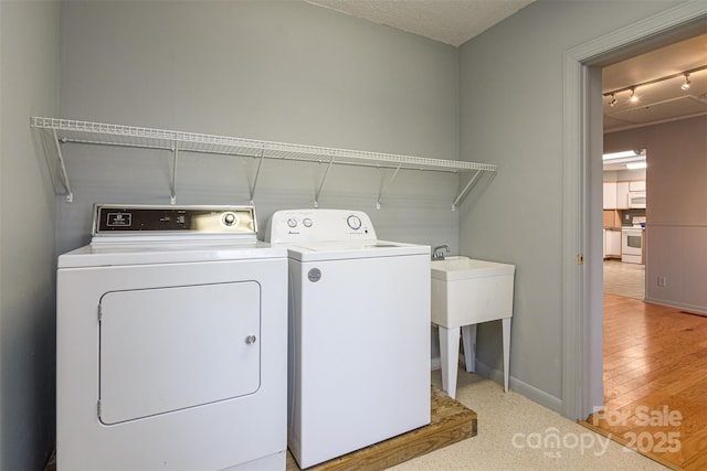 laundry area featuring washing machine and clothes dryer, track lighting, baseboards, laundry area, and a textured ceiling