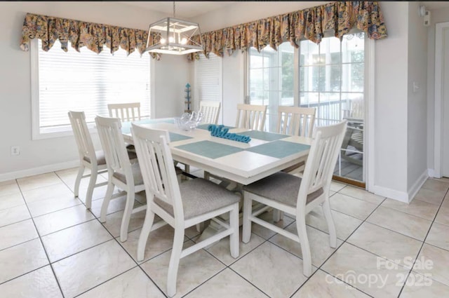 dining room with an inviting chandelier, light tile patterned flooring, and baseboards