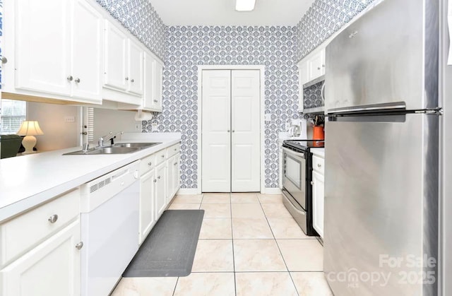 kitchen featuring white cabinets, appliances with stainless steel finishes, wallpapered walls, and a sink