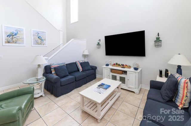 living room featuring light tile patterned floors, baseboards, and stairs