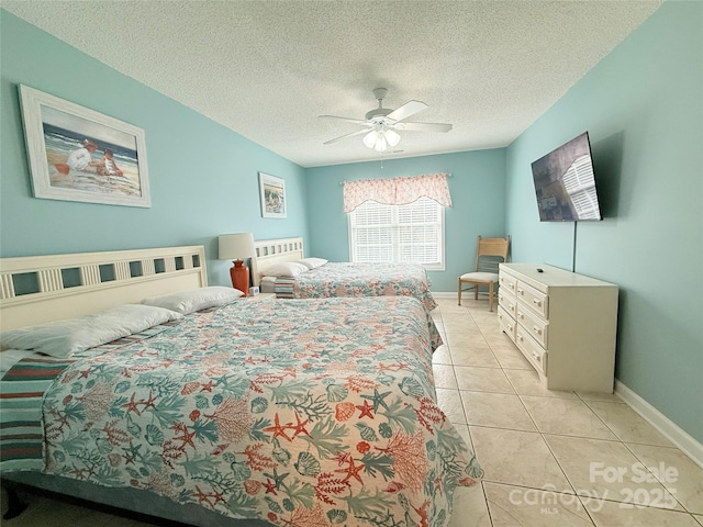 bedroom featuring light tile patterned flooring, a ceiling fan, baseboards, and a textured ceiling