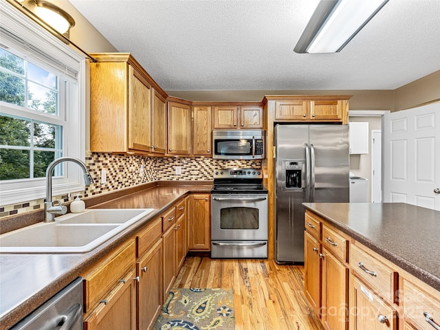 kitchen featuring a sink, dark countertops, light wood-style floors, and stainless steel appliances