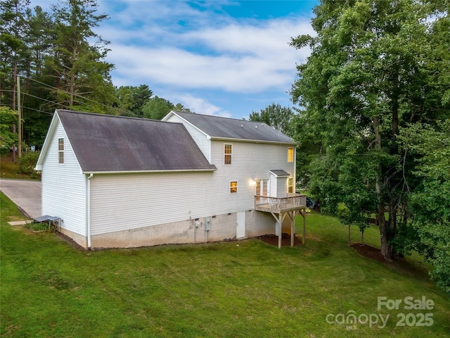 rear view of property with a yard, a wooden deck, and a shingled roof