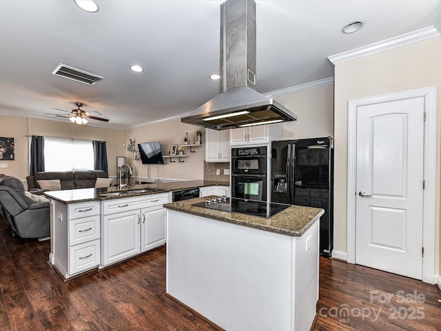 kitchen featuring visible vents, a peninsula, island range hood, black appliances, and a sink