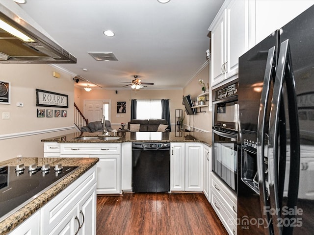 kitchen with a sink, a peninsula, black appliances, and ornamental molding