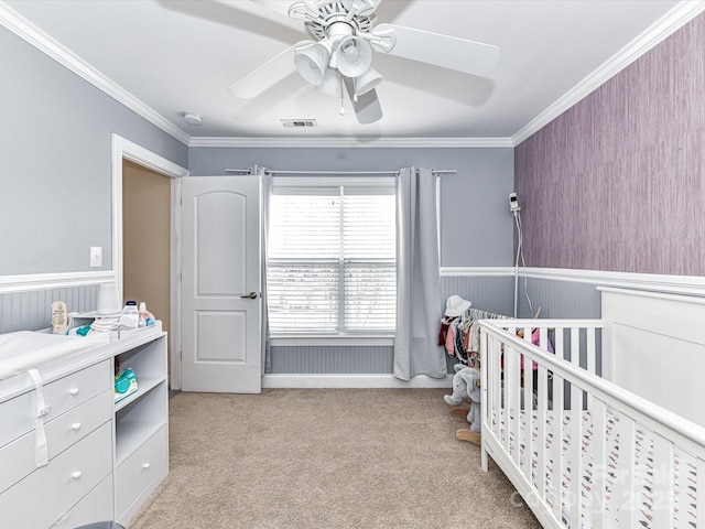 bedroom with a wainscoted wall, light colored carpet, visible vents, and ornamental molding