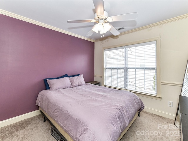 carpeted bedroom featuring visible vents, baseboards, ornamental molding, and a ceiling fan