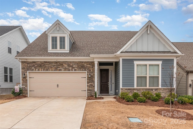 view of front facade featuring a garage, stone siding, driveway, and a shingled roof