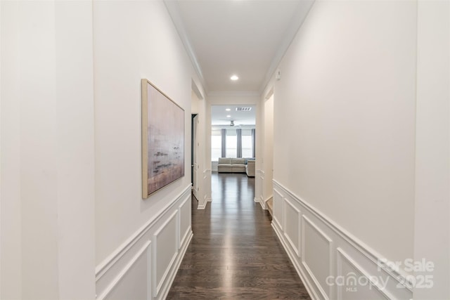 hall with visible vents, crown molding, a wainscoted wall, dark wood-style floors, and a decorative wall