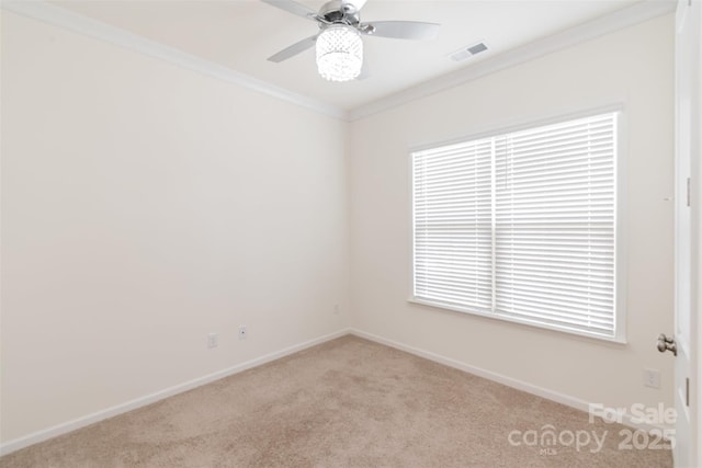 empty room featuring visible vents, ornamental molding, a ceiling fan, baseboards, and light colored carpet