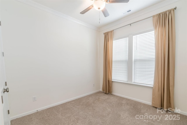 empty room featuring a ceiling fan, baseboards, visible vents, ornamental molding, and light colored carpet