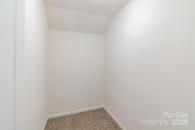 carpeted empty room with lofted ceiling and baseboards