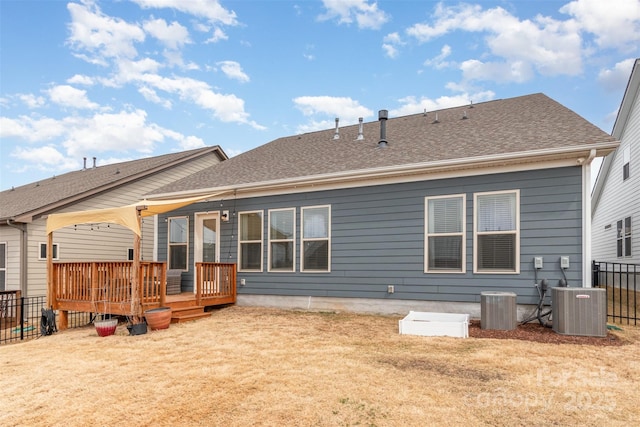 rear view of property with central air condition unit, fence, and a lawn