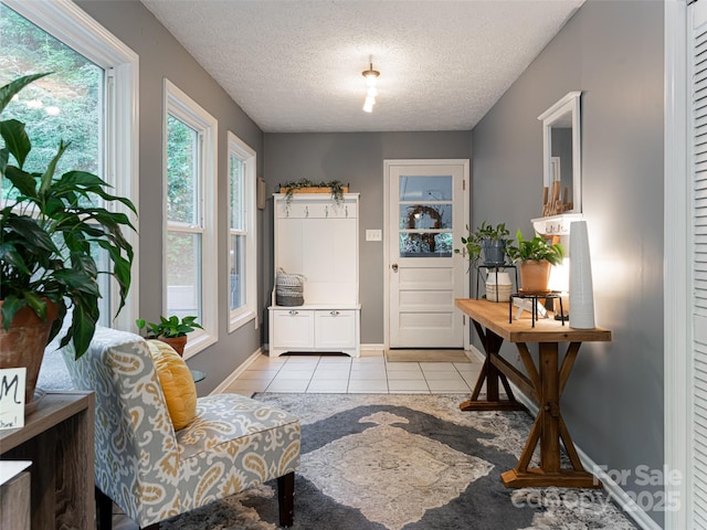 doorway featuring light tile patterned flooring, a textured ceiling, and baseboards