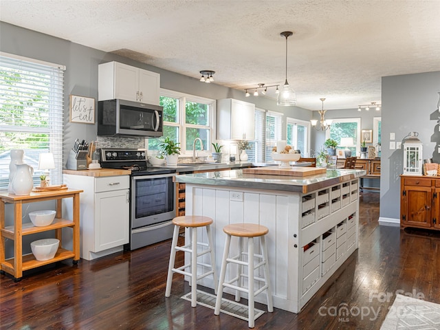 kitchen with tasteful backsplash, a center island, dark wood-type flooring, appliances with stainless steel finishes, and a sink