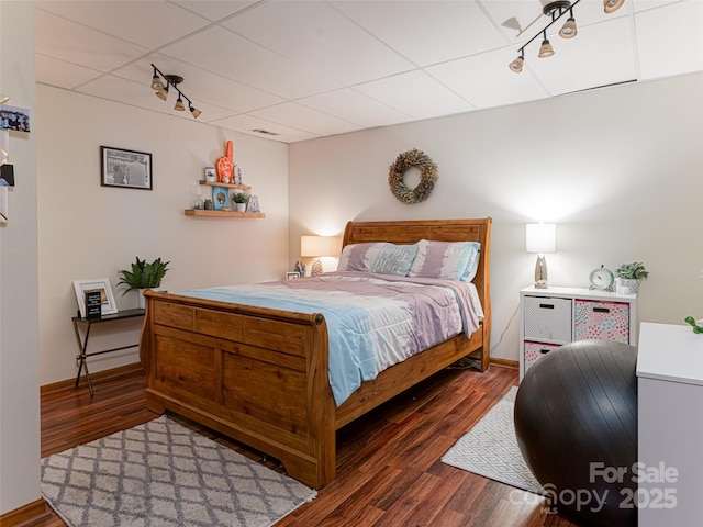 bedroom with a paneled ceiling, baseboards, and wood finished floors