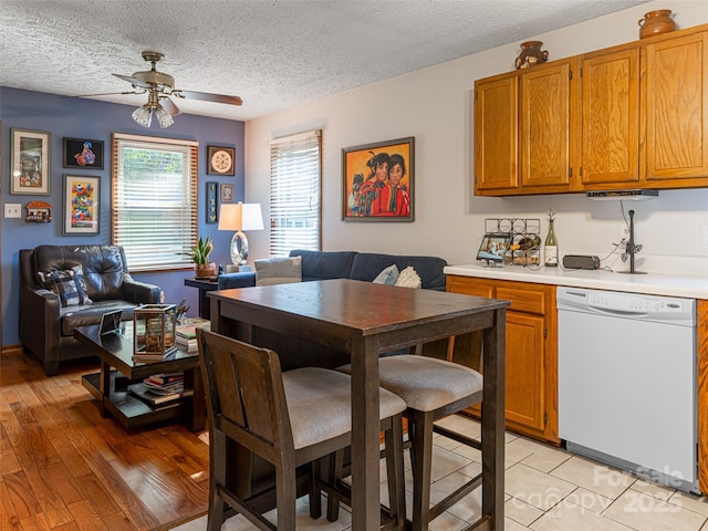 kitchen featuring a ceiling fan, light wood-style floors, brown cabinetry, light countertops, and dishwasher