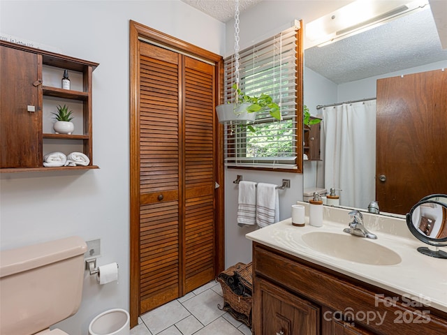 full bathroom featuring vanity, a closet, a textured ceiling, tile patterned floors, and toilet