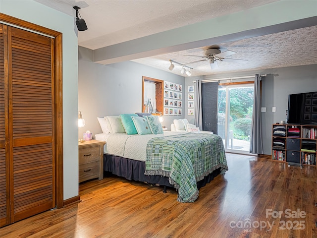 bedroom with access to exterior, a textured ceiling, and wood finished floors