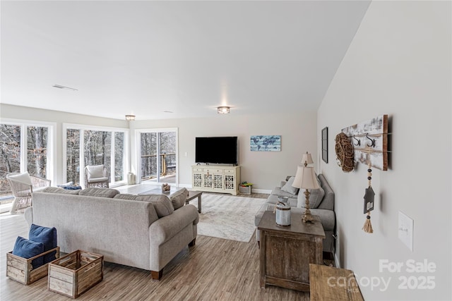 living area featuring wood finished floors, visible vents, and baseboards