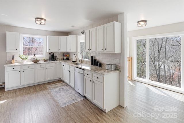 kitchen featuring a sink, light wood-type flooring, dishwasher, and white cabinets