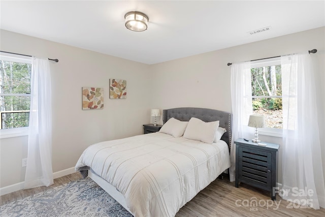 bedroom featuring wood finished floors, visible vents, and baseboards