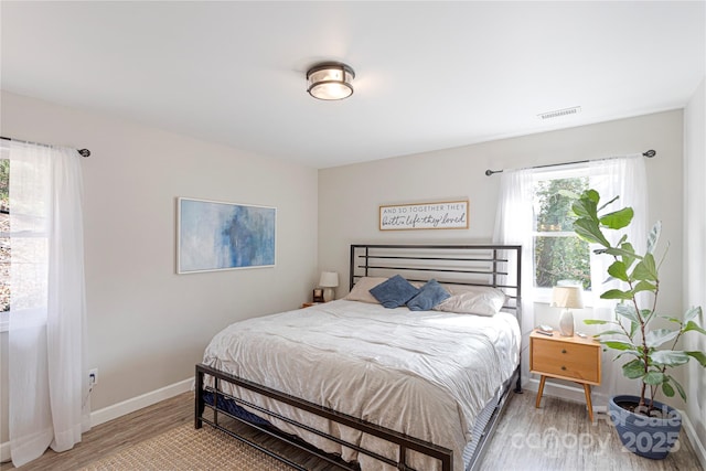 bedroom with visible vents, baseboards, and light wood finished floors