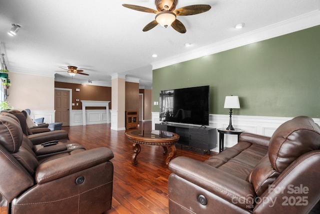 living room with crown molding, wood finished floors, wainscoting, and ceiling fan