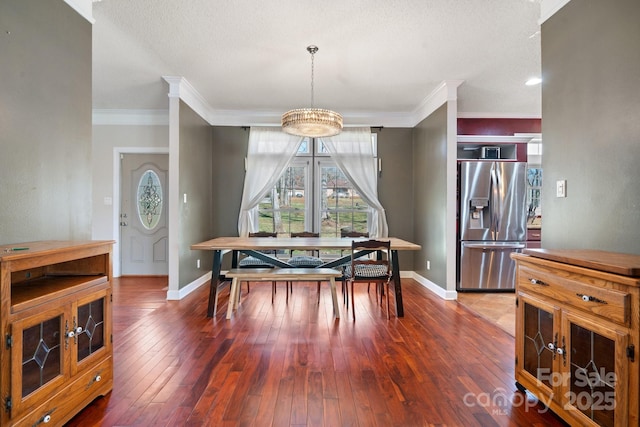 dining room featuring crown molding, baseboards, wood-type flooring, and a chandelier