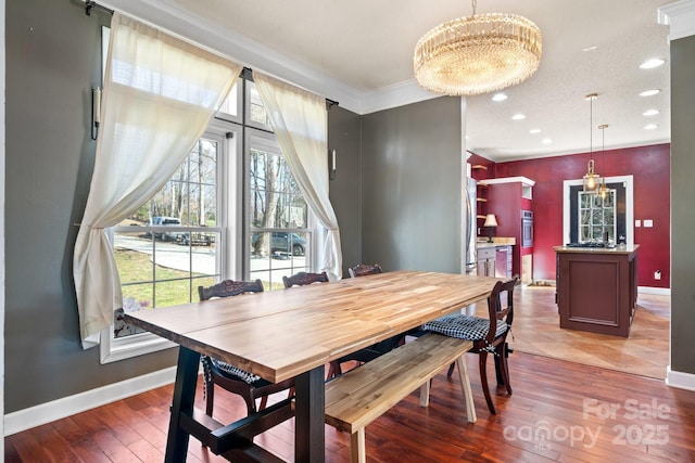 dining room with crown molding, baseboards, hardwood / wood-style floors, recessed lighting, and an inviting chandelier