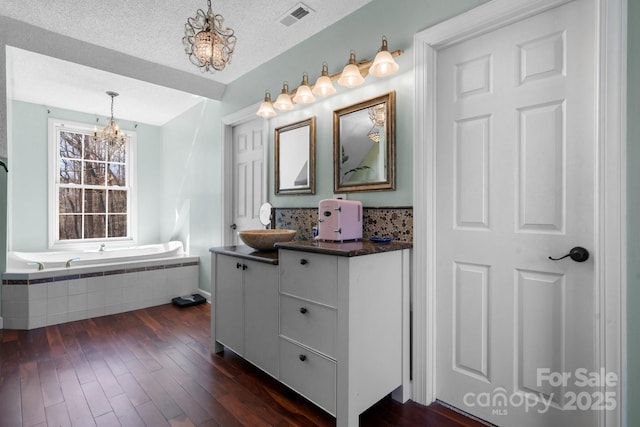 bathroom with vanity, wood finished floors, visible vents, a textured ceiling, and a chandelier