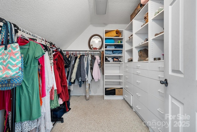 walk in closet with vaulted ceiling and carpet floors